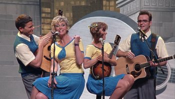 Movie still from “A Mighty Wind” (2003), directed by Christopher Guest – A group of women singing and playing musical instruments; Wide shot, High angle