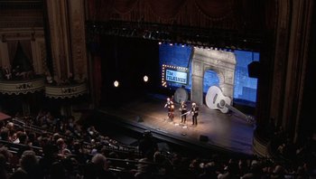 Movie still from “A Mighty Wind” (2003), directed by Christopher Guest – A group of people on a stage performing on a stage; Extreme Wide shot, High angle