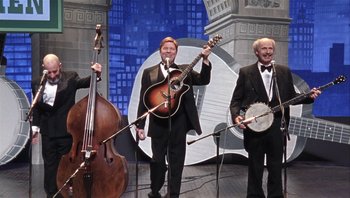 Movie still from “A Mighty Wind” (2003), directed by Christopher Guest – A group of men standing next to each other holding instruments; Wide shot, High angle