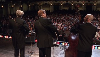 Movie still from “A Mighty Wind” (2003), directed by Christopher Guest – A group of men in suits playing a concert; Wide shot, High angle