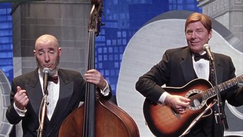 Movie still from “A Mighty Wind” (2003), directed by Christopher Guest – A couple of men in suits are playing music; Medium shot, Low angle