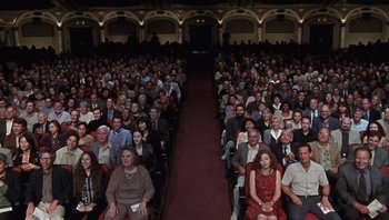 Movie still from “A Mighty Wind” (2003), directed by Christopher Guest – A large group of people sitting in rows in a theater; Wide shot, High angle