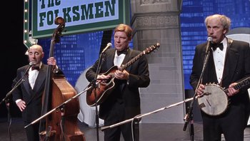 Movie still from “A Mighty Wind” (2003), directed by Christopher Guest – A man in a black suit playing an instrument; Medium shot, High angle
