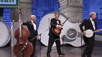 Movie still from “A Mighty Wind” (2003), directed by Christopher Guest – Two men in suits are playing a song on a stage; Wide shot, Low angle