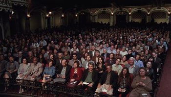 Movie still from “A Mighty Wind” (2003), directed by Christopher Guest – A large group of people sitting in a theater; Extreme Wide shot, High angle