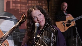 Movie still from “A Mighty Wind” (2003), directed by Christopher Guest – A woman holding an accordion while standing next to a microphone; Close Up shot, Low angle