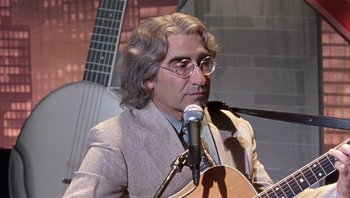 Movie still from “A Mighty Wind” (2003), directed by Christopher Guest – A man in a suit is playing a guitar; Close Up shot, Over the shoulder angle