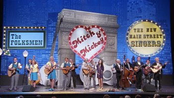 Movie still from “A Mighty Wind” (2003), directed by Christopher Guest – A group of people standing on a stage holding guitars; Wide shot, High angle
