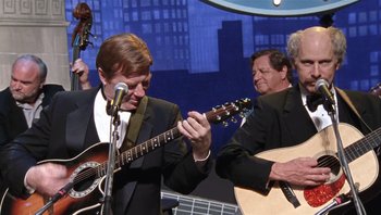 Movie still from “A Mighty Wind” (2003), directed by Christopher Guest – A man in a black suit playing an instrument; Medium shot, Over the shoulder angle