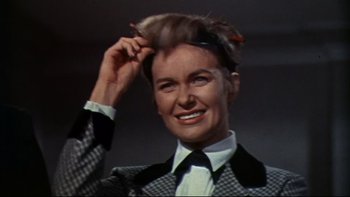 Movie still from “A New Kind of Love” (1963), directed by Melville Shavelson – A woman in a black and white suit holding her hair up; Close Up shot, Low angle
