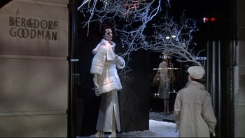 Movie still from “A New Kind of Love” (1963), directed by Melville Shavelson – A woman in a white coat standing in front of a store window; Wide shot, Low angle