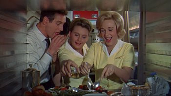 Movie still from “A New Kind of Love” (1963), directed by Melville Shavelson – A group of people standing around a table with food on top of it; Medium shot, Low angle