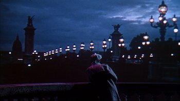 Movie still from “A New Kind of Love” (1963), directed by Melville Shavelson – A person standing in front of a bridge at night; Wide shot, Low angle