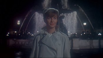 Movie still from “A New Kind of Love” (1963), directed by Melville Shavelson – A woman in a white coat standing in front of a fountain at night; Medium shot, Low angle