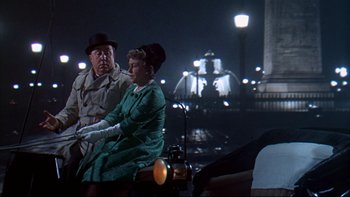 Movie still from “A New Kind of Love” (1963), directed by Melville Shavelson – An older man and woman sitting next to each other in front of lights at night; Medium shot, Over the shoulder angle