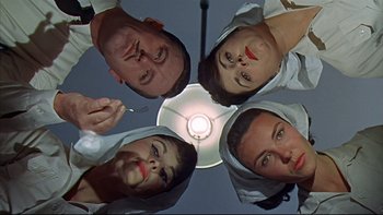 Movie still from “A New Kind of Love” (1963), directed by Melville Shavelson – A group of people standing under a light; Close Up shot, Overhead angle