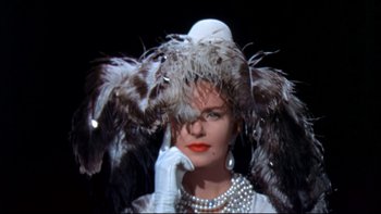 Movie still from “A New Kind of Love” (1963), directed by Melville Shavelson – A woman in a white dress with feathers on her head; Close Up shot, Low angle
