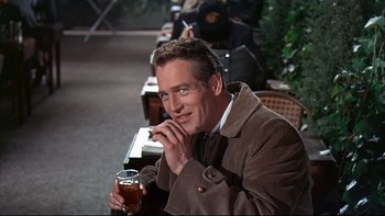 Movie still from “A New Kind of Love” (1963), directed by Melville Shavelson – A man sitting at a table with a glass of beer in front of him; Medium shot, Over the shoulder angle