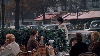 Movie still from “A New Kind of Love” (1963), directed by Melville Shavelson – A group of people sitting at an outdoor restaurant; Wide shot, Over the shoulder angle