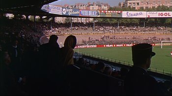 Movie still from “A New Kind of Love” (1963), directed by Melville Shavelson – Two people are standing in the stands at a baseball game; Extreme Wide shot, High angle