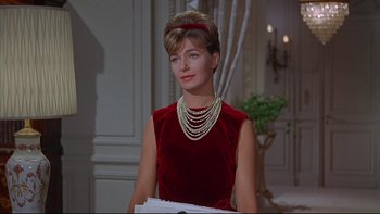 Movie still from “A New Kind of Love” (1963), directed by Melville Shavelson – A woman in a red dress and pearls in a room; Close Up shot, Low angle