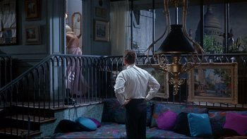 Movie still from “A New Kind of Love” (1963), directed by Melville Shavelson – A man standing in front of a window looking at a woman; Wide shot, High angle