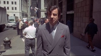Movie still from “A New Leaf” (1971), directed by Elaine May – A man in a suit and tie standing on the sidewalk; Medium shot, High angle