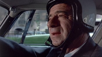 Movie still from “A New Leaf” (1971), directed by Elaine May – An older man wearing a helmet driving a car; Close Up shot, Low angle