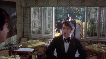 Movie still from “A New Leaf” (1971), directed by Elaine May – A man in a tuxedo standing in a restaurant; Medium shot, Over the shoulder angle