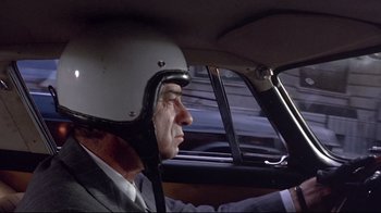 Movie still from “A New Leaf” (1971), directed by Elaine May – A man wearing a helmet sitting in the driver's seat of a car; Close Up shot, Low angle