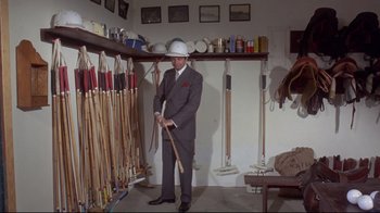 Movie still from “A New Leaf” (1971), directed by Elaine May – A man in a gray suit and white hat holding a baseball bat; Wide shot, High angle