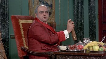 Movie still from “A New Leaf” (1971), directed by Elaine May – A man sitting in a chair holding a wooden stick; Medium shot, Over the shoulder angle