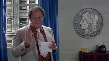 Movie still from “A New Leaf” (1971), directed by Elaine May – A man in a suit and tie holding a piece of paper in his hand; Medium shot, Over the shoulder angle