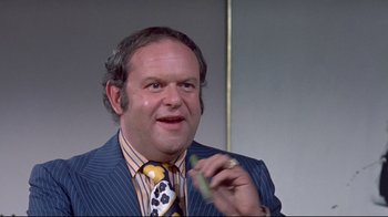 Movie still from “A New Leaf” (1971), directed by Elaine May – A man in a suit and tie holding a pen in his hand; Close Up shot, Low angle