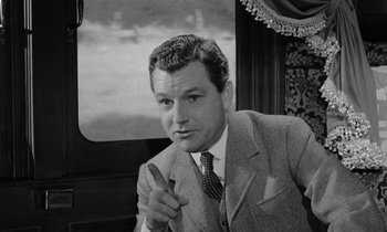 Movie still from “A Night to Remember” (1958), directed by Roy Ward Baker – A black and white photo of a man in a suit and tie; Medium shot, Low angle