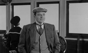 Movie still from “A Night to Remember” (1958), directed by Roy Ward Baker – A black and white photo of a man in a suit and tie; Medium shot, Low angle