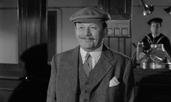 Movie still from “A Night to Remember” (1958), directed by Roy Ward Baker – An older man wearing a suit and a hat; Medium shot, Low angle
