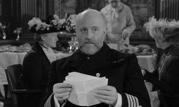 Movie still from “A Night to Remember” (1958), directed by Roy Ward Baker – An older man in a naval uniform holding a piece of paper; Close Up shot, Over the shoulder angle