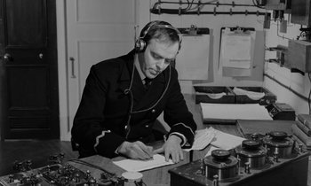 Movie still from “A Night to Remember” (1958), directed by Roy Ward Baker – A man wearing headphones writing on a piece of paper; Medium shot, Low angle