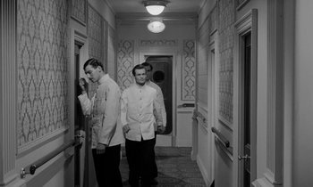 Movie still from “A Night to Remember” (1958), directed by Roy Ward Baker – A couple of men standing next to each other in a hallway; Medium shot, High angle