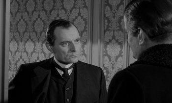 Movie still from “A Night to Remember” (1958), directed by Roy Ward Baker – A black and white photo of a man in a suit; Close Up shot, Over the shoulder angle