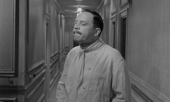 Movie still from “A Night to Remember” (1958), directed by Roy Ward Baker – A black and white photo of a man standing in a hallway; Medium shot, Low angle