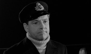 Movie still from “A Night to Remember” (1958), directed by Roy Ward Baker – Black and white photograph of a man wearing a hat; Close Up shot, Low angle