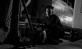 Movie still from “A Night to Remember” (1958), directed by Roy Ward Baker – An old man sitting on the ground in a dark room; Medium shot, Low angle