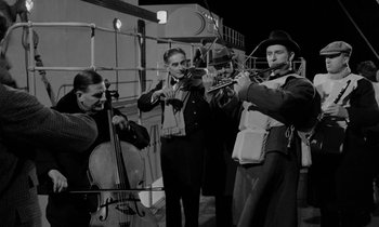 Movie still from “A Night to Remember” (1958), directed by Roy Ward Baker – A black and white photo of a group of people playing instruments; Medium shot, Low angle