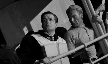 Movie still from “A Night to Remember” (1958), directed by Roy Ward Baker – A man holding a baseball bat next to another man; Medium shot, Low angle
