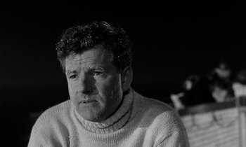 Movie still from “A Night to Remember” (1958), directed by Roy Ward Baker – Black and white photograph of a man in a sweater; Close Up shot, Low angle