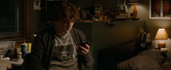 Movie still from “A Nightmare on Elm Street” (2010), directed by Samuel Bayer – A man looking at his cell phone while sitting in a room; Medium shot, High angle