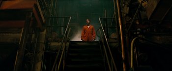 Movie still from “A Nightmare on Elm Street” (2010), directed by Samuel Bayer – A man in an orange shirt standing on some stairs; Wide shot, Low angle