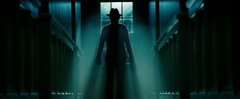Movie still from “A Nightmare on Elm Street” (2010), directed by Samuel Bayer – A man wearing a hat standing in front of a window; Wide shot, Low angle
